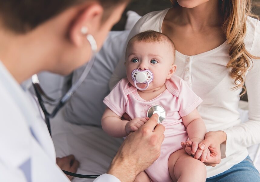 Beautiful young mom is holding her cute baby while doctor is listening to baby's lungs